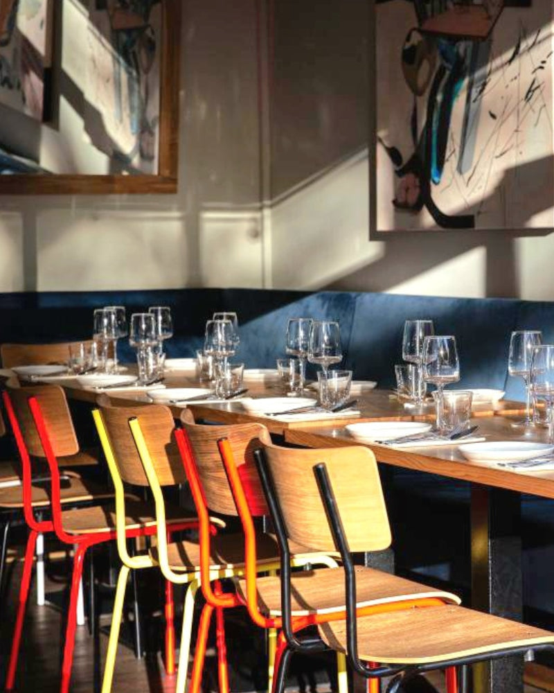 Bunte Stuehle aus Eichenholz mit farbigen Stahlgestell an Dinner Tisch im Restaurant